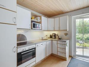 una cucina con mobili bianchi e una grande finestra di Holiday Home Uffe - 100m to the inlet by Interhome a Gråsten