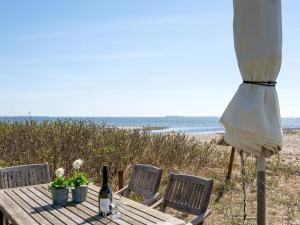 a table with a bottle of wine and an umbrella on the beach at Holiday Home Ose - 50m from the sea by Interhome in Sønder Stenderup