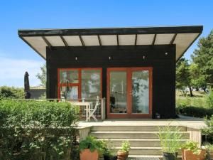 a black house with red windows and a porch at Holiday Home Pirjo - 50m from the sea by Interhome in Haderslev