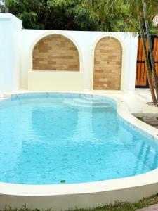 ein Swimmingpool mit blauem Wasser vor zwei Bögen in der Unterkunft 2BR Pool Villa&Garden - Bali style by La Perla Phuket Rawai in Ban Saiyuan (1)