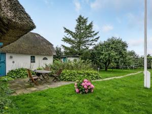 a yard with a house with a table and flowers at Holiday Home Clausina - 600m from the sea by Interhome in Bredebro