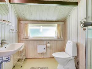 a bathroom with a toilet and a sink and a window at Holiday Home Rentje - 31km from the sea by Interhome in Toftlund
