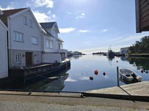 a river with a house and a boat in the water at Ocean Front Garden in Skudeneshavn