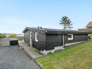 a small black house with a wooden porch at Holiday Home Elain - from the sea by Interhome in Broager