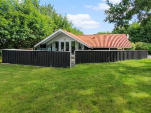 a house with a fence in front of a yard at Holiday Home Carlotta - 12km from the sea by Interhome in Oksbøl
