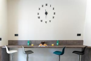a clock on a wall above a counter with chairs at KM30rooms in Campobasso
