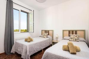 two beds in a room with two windows at Villa Gregal in Cala Blanca +13 photos