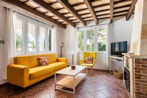 a living room with a yellow couch and a tv at Villa Gregal in Cala Blanca