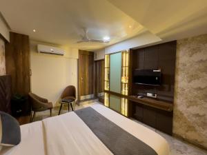 a hotel room with a bed and a flat screen tv at Hotel Ratna Paradise Thane West in Thane