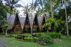una casa con techo de paja y palmeras en Jungle House Estate, en Gianyar