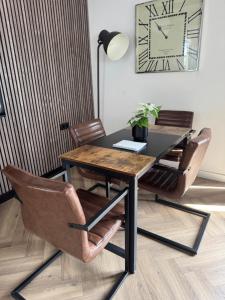 a dining room table and chairs with a clock on the wall at Smile home 2, Zaanse schans and Amsterdam Appartements in Wormerveer