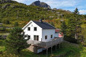 a white house on a deck with mountains in the background at Oceanview Escape Lofoten in Ramberg