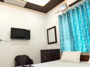 a room with a bed and a tv on the wall at B K Palace in Ayodhya