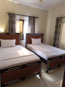 two beds in a room with two windows at Modern Stand alone estate house in Mombasa