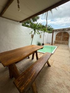 a wooden bench sitting on a patio with a pool at Casa Branca Mediterrânea in Barra Grande