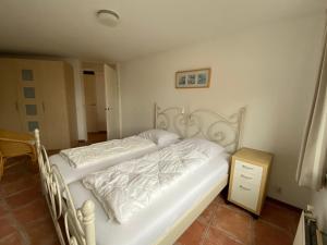 een slaapkamer met een wit bed en een nachtkastje bij Callantsoger Staete A112 in Callantsoog