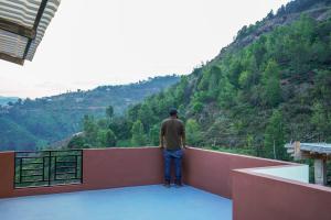 a man standing on a ledge looking at a mountain at Climate Dull - Homestay Villa in Ketti +2 photos