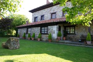 a stone house with a tree stump in front of it at Apartamentos Rurales Colsa in Colsa