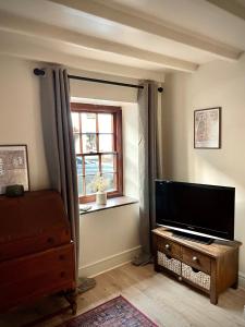 een woonkamer met een flatscreen-tv en een raam bij Poets Cottage Eglwys Fach in Eglwys-fach
