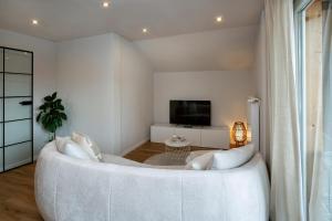 a living room with a white couch and a tv at Pension Elisa in Lechbruck
