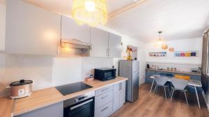 une cuisine avec des armoires blanches et une table et des chaises dans l'établissement Appartement COCO T4 en R+1 proche du lagon, à La Saline les Bains