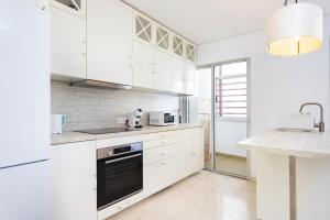 Una cocina con gabinetes blancos y un horno de estufa. en Spacious 3-Bedroom Apartment with Pool & Balcony - Steps from Puerto Colón, Beach & All Local Attractions, en Adeje
