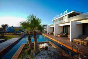a building with a swimming pool with palm trees in front of it at VENTO MARE Çeşme in Çeşme