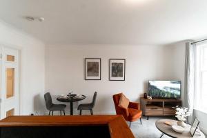a living room with a tv and a table and chairs at Lovely 1 Bed Harbour-side Apartment - Sea Views in Whitehaven