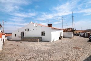 a white building on a cobblestone street at Casa Gotinha d' Água in Alcaria Ruiva