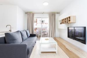 Una sala de estar con un sofá azul y un televisor. en Spacious 3-Bedroom Apartment with Pool & Balcony - Steps from Puerto Colón, Beach & All Local Attractions, en Adeje