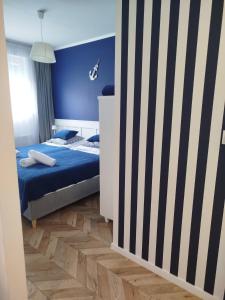 a bedroom with a bed and a blue wall at Trimare Blue Apartament Sztutowo in Sztutowo