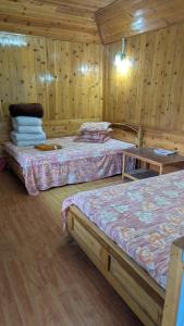 deux lits dans une chambre aux murs en bois dans l'établissement Kynance Homestay, à Kalimpong