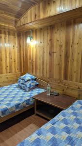 - une chambre avec 2 lits et un mur en bois dans l'établissement Kynance Homestay, à Kalimpong
