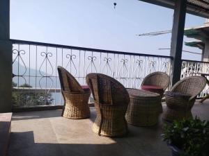 - un balcon avec des tables et des chaises en osier dans l'établissement Kynance Homestay, à Kalimpong