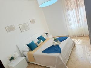 a white bedroom with a bed with blue pillows at Home Sisters in Trapani