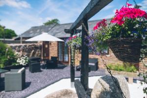 eine Terrasse mit Blumen in einem Korb auf einer Stange in der Unterkunft Wisteria Cottage Wye Valley AONB in Llangarren + 20 Fotos