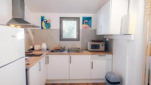 Una cocina con gabinetes blancos y un microondas. en Studio PASSION en RDJ proche du lagon, en La Saline-Les-Bains