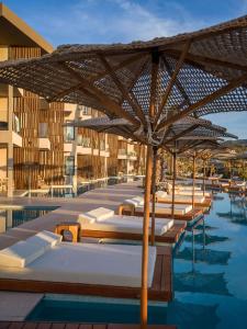 a pool with a bunch of chairs and an umbrella at Nalu Resort & SPA Adults Only Hotel in Adelianos Kampos