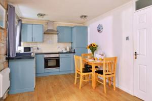eine Küche mit blauen Schränken und einem Tisch mit Stühlen in der Unterkunft Finest Retreats - Joyful Cottage in Saint Erth