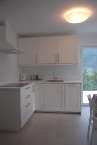 a kitchen with white cabinets and a large window at Apartma Neža in Bled