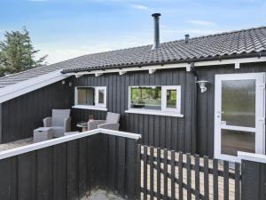 una casa negra con ventanas blancas y una valla en Holiday Home Blondine - 940m from the sea by Interhome, en Hjørring