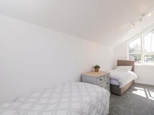 a white bedroom with a bed and a window at 6 Newbridge Gardens in Bath