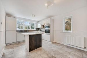 イルクリーにあるStylish home close to the Yorkshire Dales & Leeds Airportの白いキャビネットと大きな島のあるキッチン