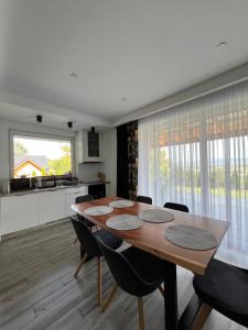 a kitchen and dining room with a wooden table and chairs at Domek nad Doliną Dunajca - Malo Stay in Zakliczyn