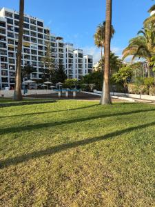 a park with palm trees and a large building at Apartamento céntrico en Playa de Las Américas in Costa de Adeje