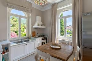 a kitchen with a table and a sink and windows at Villa Barbarano - villa privata con accesso al lago in Montecucco