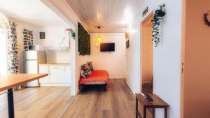 a living room with a red chair and a kitchen at Appart. VANILLE T3 en RDJ proche du lagon in Saint-Gilles les Bains