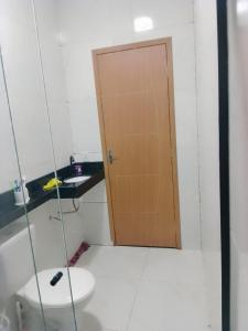 a bathroom with a toilet and a wooden door at Casa dos sonhos in Viçosa do Ceará