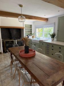 a kitchen with a wooden table with chairs and a counter at Maison TENERYL ancien corps de ferme rénové in Saint-Benoît-sur-Loire