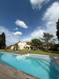 a swimming pool in front of a house at Maison TENERYL ancien corps de ferme rénové in Saint-Benoît-sur-Loire